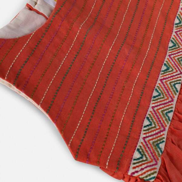 Close-up of chic burnt-orange linen dress with colourful embroidered waistline and Kantha-work hand-embroidered bodice