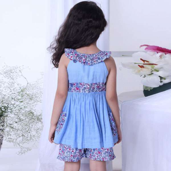 Rear image of a girl in blue double gauze cotton tunic with floral details paired with matching floral shorts