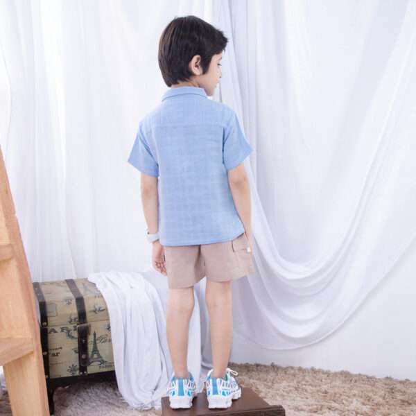 Back view of a small boy dressed in an aqua gauze shirt and khaki shorts withcargo pockets