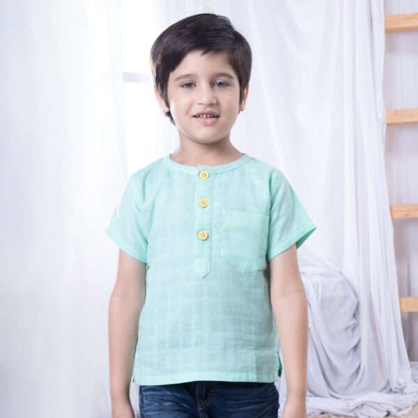 Close-up of a boy in aqua gauze boy's shirt with hand embroidered front pocket and yellow buttons