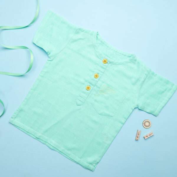 Flatlay of aqua gauze boy's shirt with hand embroidered front pocket and yellow buttons