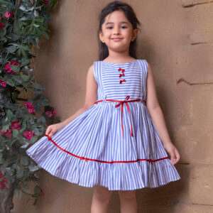 A little girl wearing sleeveless blue striped dress with satin bows on the hem ruffle and bodice and a red satin belt
