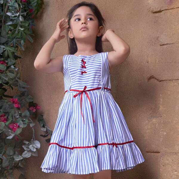 Little girl flaunting blue striped cotton dress with red satin ribbon bows, belt and hem trims