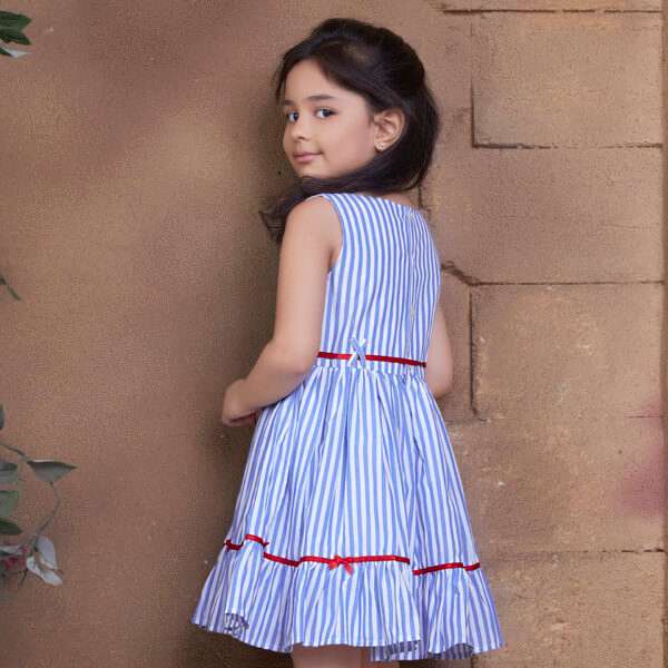 Rear image of a girl in blue striped cotton sleeveless dress with red satin ribbon belt