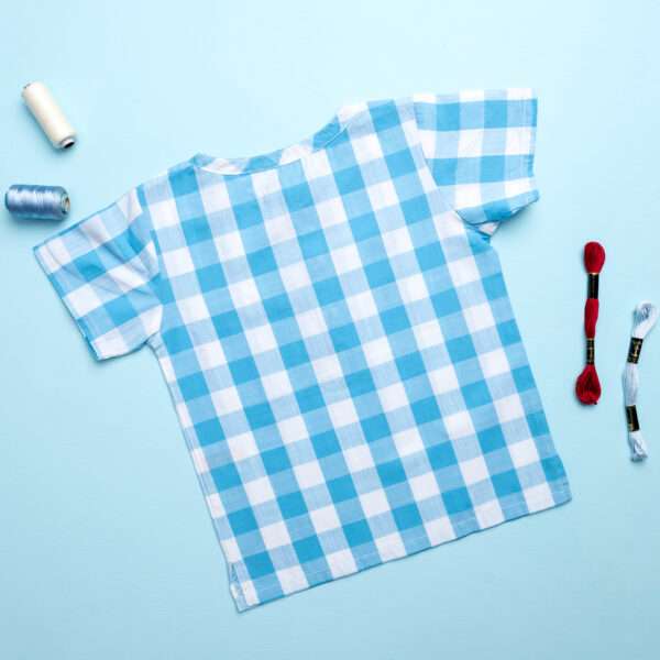 Boys blue check half sleeve shirt laid out with matched thread skeins