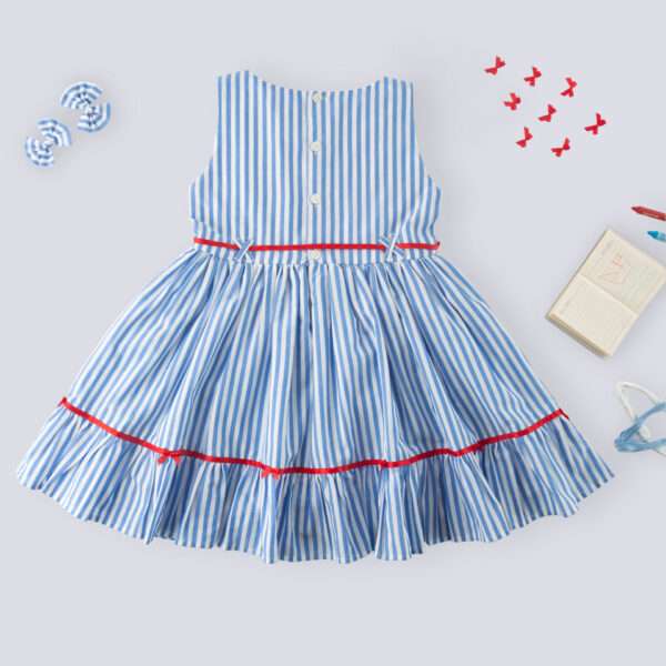 Flatlay of rear side of blue stripe cotton dress with satin bows on the hem ruffle and bodice, a satin belt at the waist