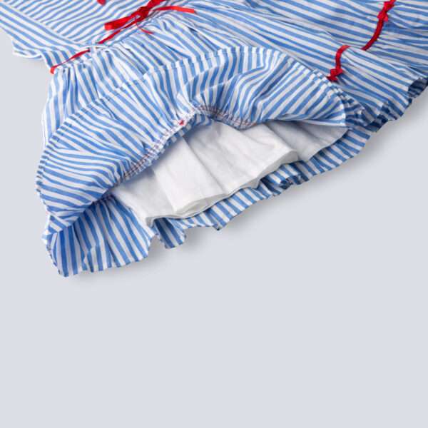 Close-up of hem of blue stripe dress with satin bows on the hem ruffle and bodice, a satin belt at the waist