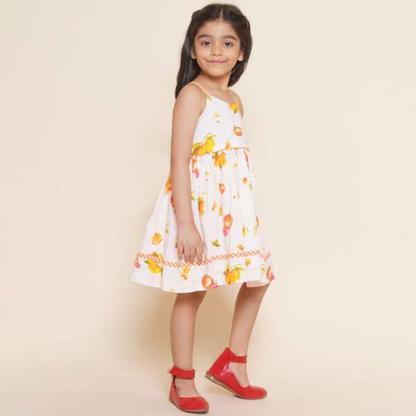 Little girl in pink vibrant fruit print dress with lemons, tangerines and daisies and orange gingham trims