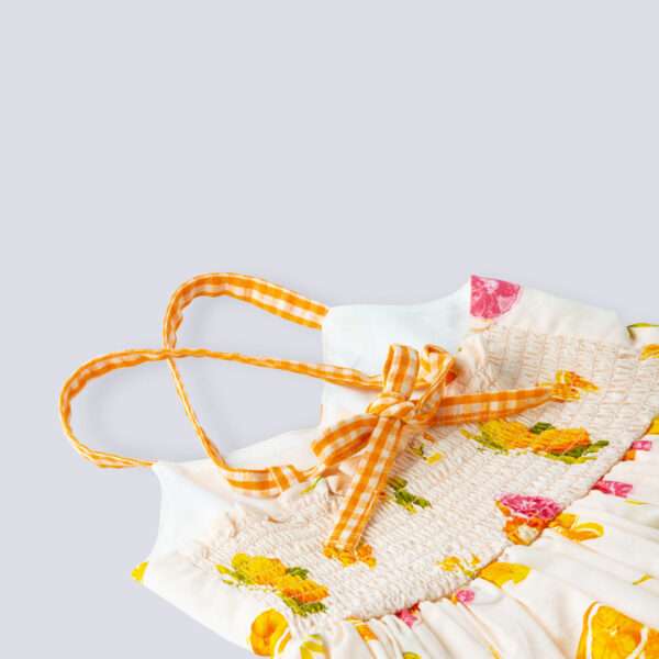 Close-up of pink vibrant fruit print dress with lemons, tangerines and daisies and orange gingham trims