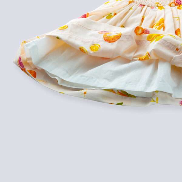 Close-up of pink vibrant fruit print dress with lemons, tangerines and daisies and orange gingham trims