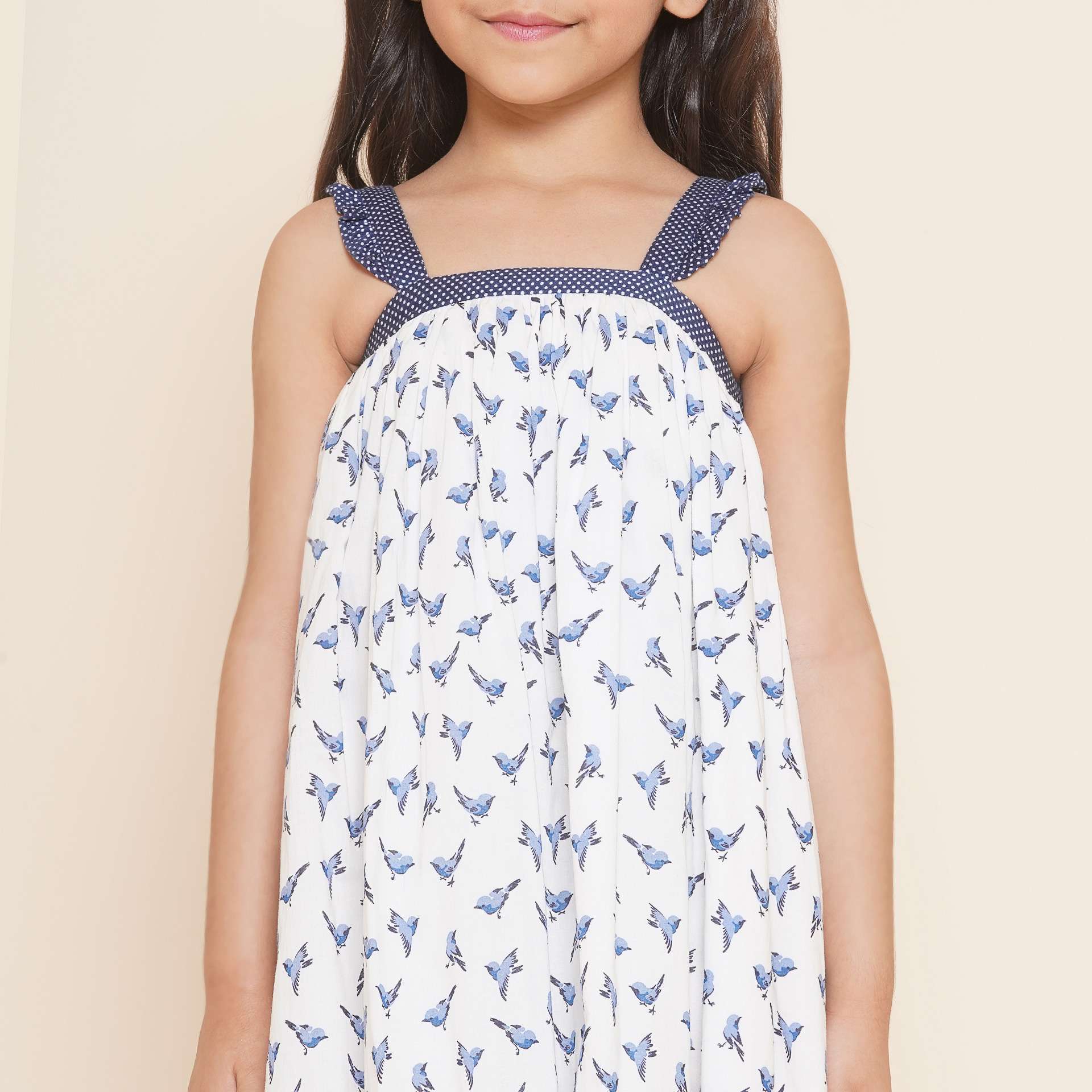 Closeup shot of a girl wearing strappy shoulder dress with blue bird print and tiny ruffles on the shoulder straps
