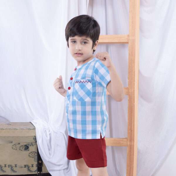 A boy in a striking blue checked shirt with bold red chevron hand-embroidered front pocket and bright red buttons