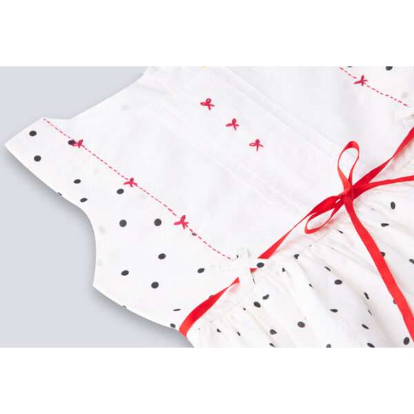 Close-up of hand embroidered yoke in sleeveless polka dot ivory cotton dress with red satin belt