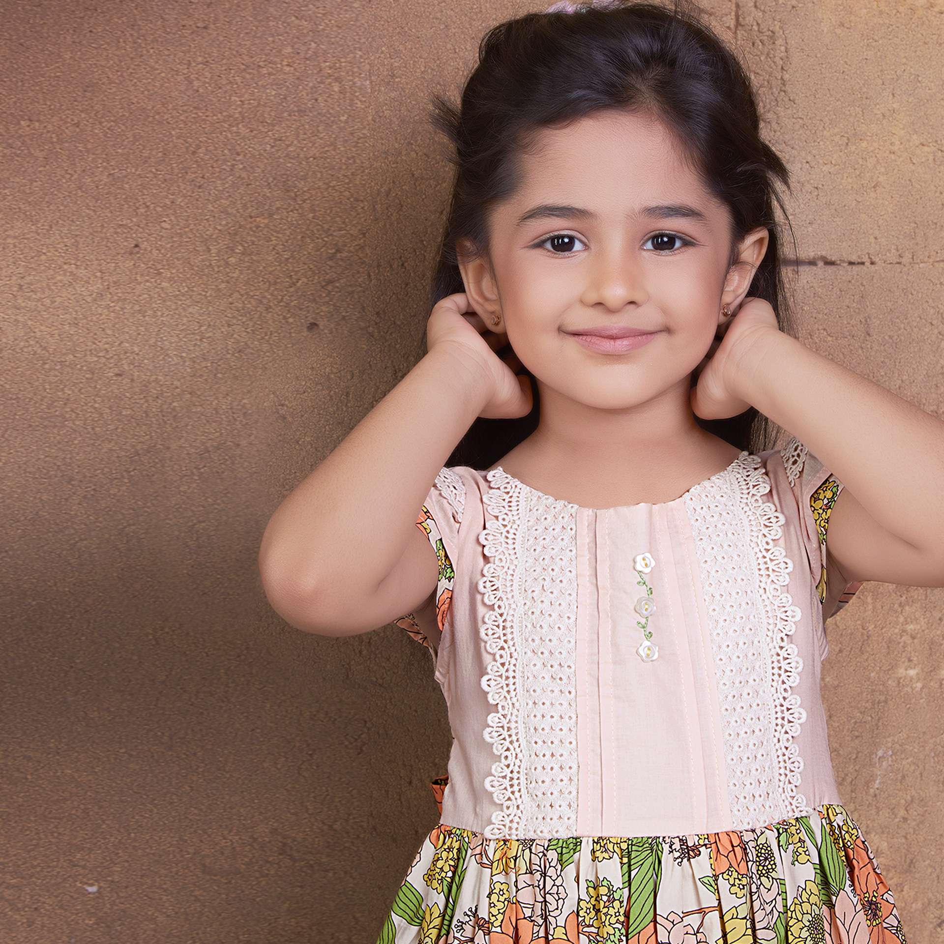 Close up image of a girl in floral cotton dress with a peach yoke featuring beautiful lace trims and hand embroidery