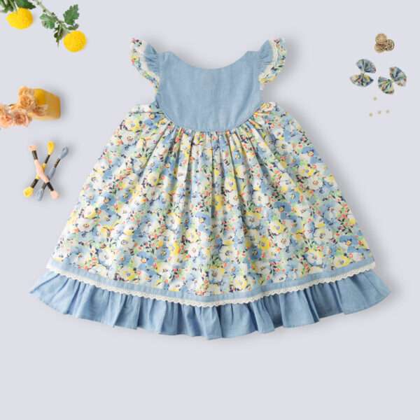 Rear side of blue chambray floral printed cotton dress with flutter sleeves, eyelet lace trims and ruffled hem