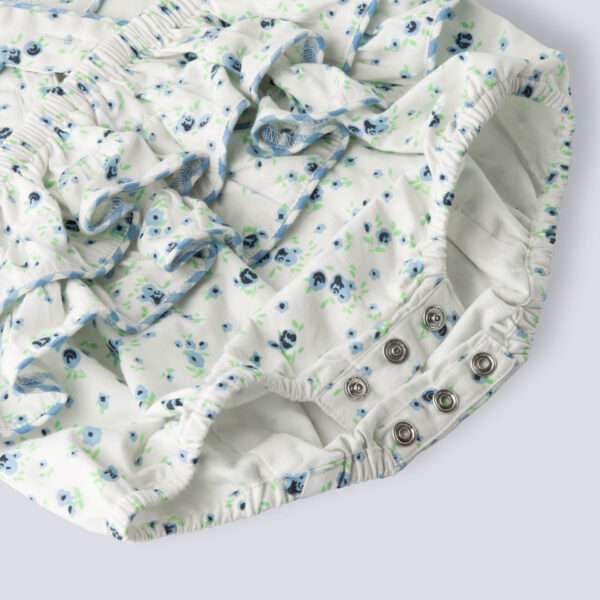 Close-up of blue floral printed onesie with back crossover straps and ruffles on the bottom with contrast trims