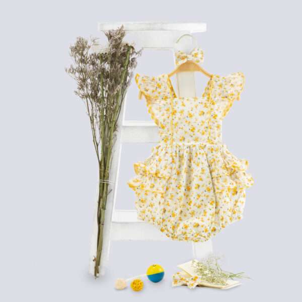 Image of yellow floral printed onesie with back crossover straps and ruffles on the bottom with contrast trims