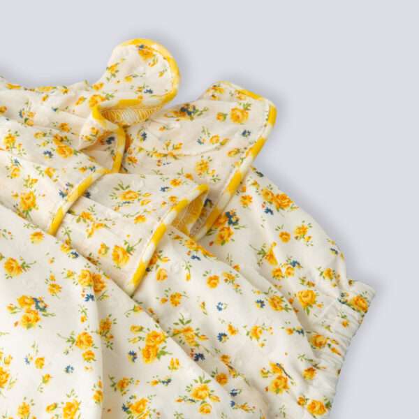 Flatlay image of bottom ruffles of yellow floral printed onesie with back crossover straps with contrast trims