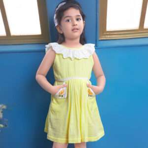 A girl in a sleeveless bright yellow gauze dress with intricate hand embroidery, ruffled neckline and shorts