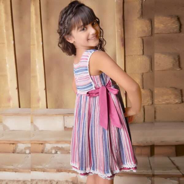 A little girl in multi-color stripe dress with side ties with bow detail on neckline and lace trims