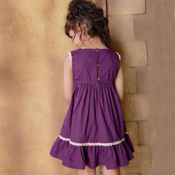 Rear side of a girl in magenta dress with hand embroidered floral garlands, embellished with woven lace, wooden buttons