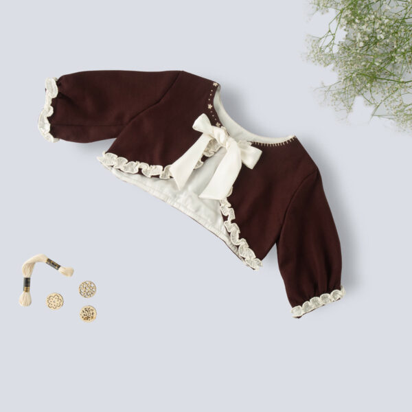 Flat lay view of a brown bolero embroidered jacket for girls featuring a tie-up sash bow with props