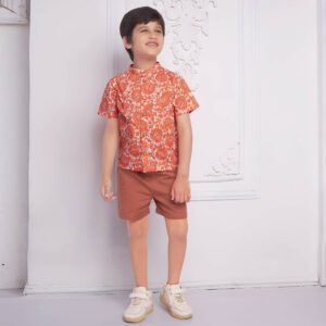 Smiling boy wearing an orange floral printed mandarin collared shirt matched with rust short