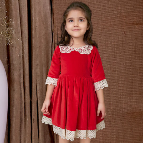 Cute girl in red velvet dress adorned with white lace