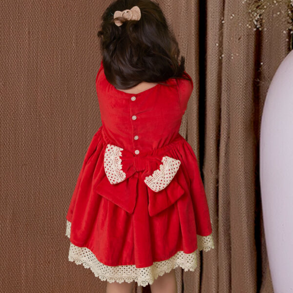 Girl seen from behind wearing a red velvet dress with an attached bow at the back
