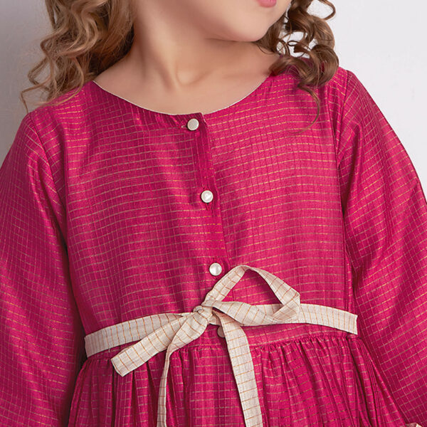 Close-up of a pink and ivory Chanderi dress fastened with front pearl buttons and a tie-up sash