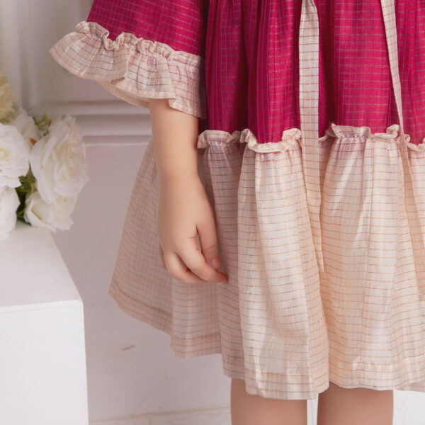 Closeup of the ruffles in pink and ivory chanderi dress with front tie up sash