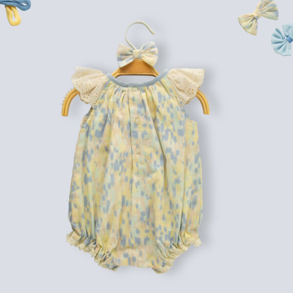 Flat lay of back view of a water color smocked onesie for baby girls, with delicate lace