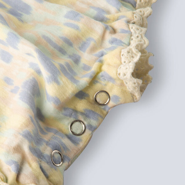 Close-up of snap buttons on a watermelon baby girl onesie, adorned with delicate lace.