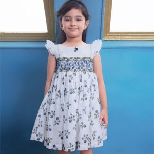 Posing with a bright smile, a little girl in a white floral printed smocked dress