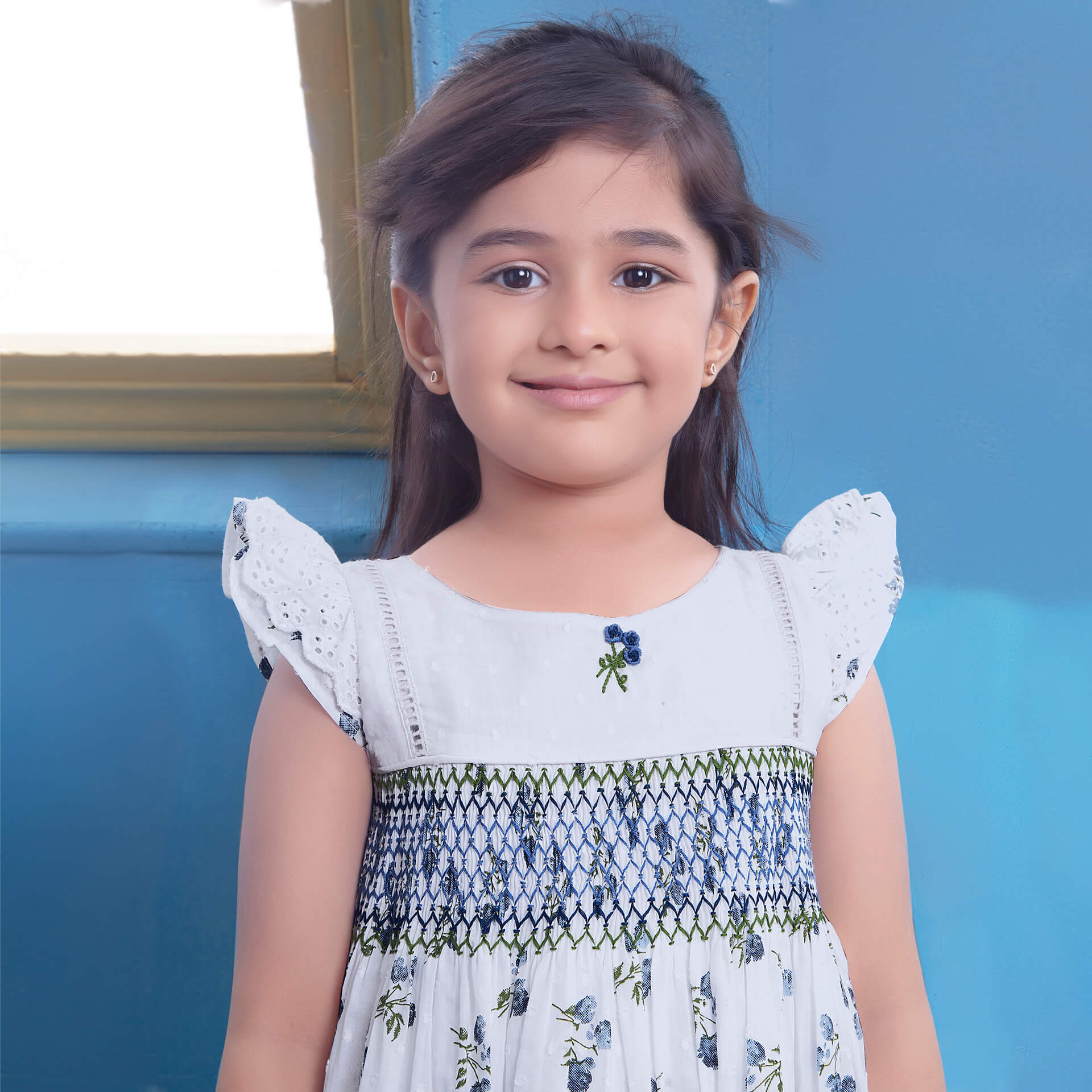 Close up of a girl posing with a bright smile in a white swiss dot floral printed smock dress