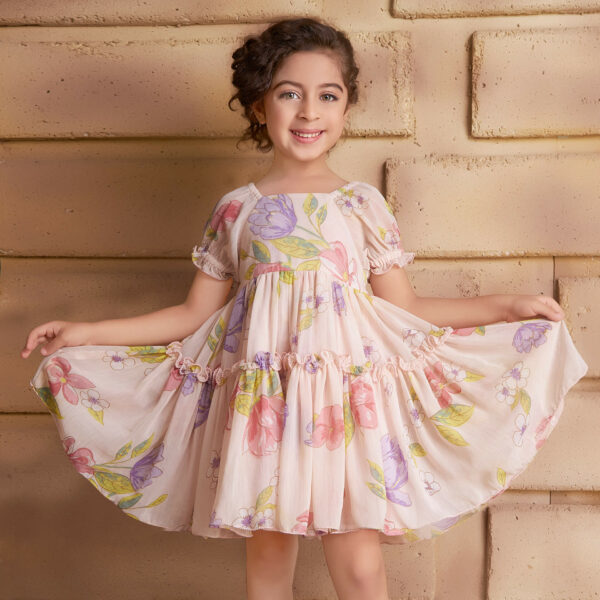 Posing in a pink chiffon dress, the girl playfully stretches the skirt with both hands
