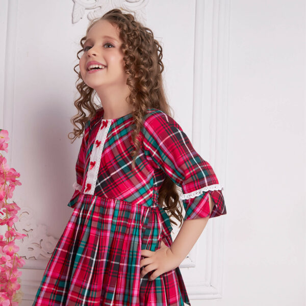 Laughing girl dressed in red plaid dress with white lace and red satin bows as trims