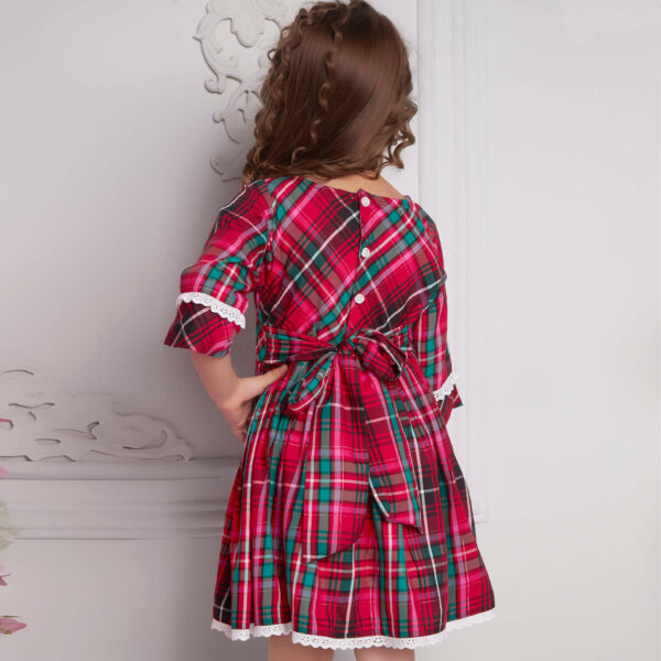Back view of a girl wearing a red plaid dress with back-fastened buttons and a tie-up sash, adorned with white lace trims