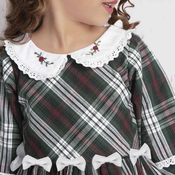 Close-up of embroidered Peter Pan collars and bow detail on a green tartan dress.