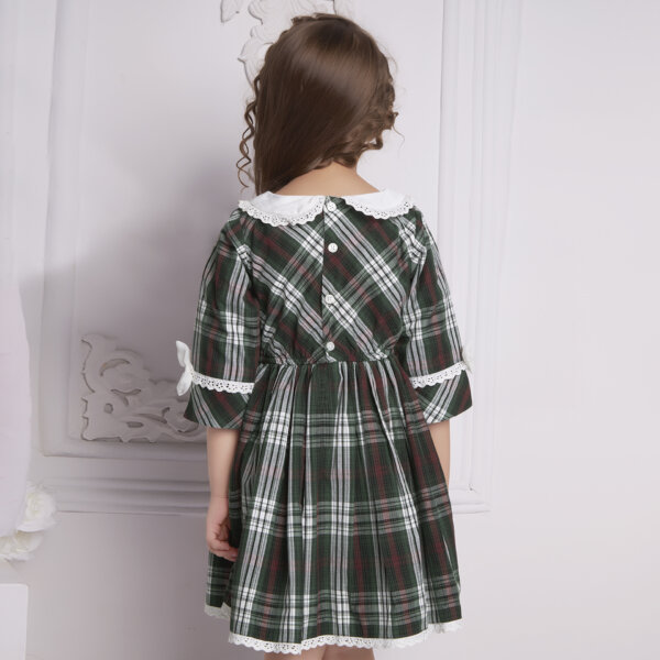 Girl seen from behind wearing a green tartan collared dress with white trims