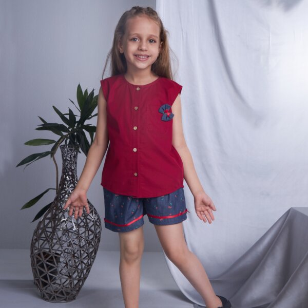 Young girl in red sleeveless blouse and navy blue shorts with bow detail
