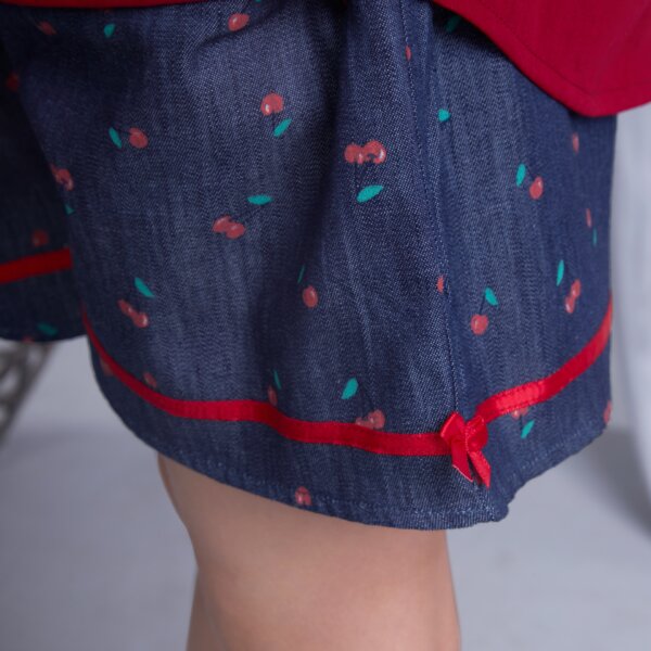 Red satin bow on a navy cherry printed shorts captured up close