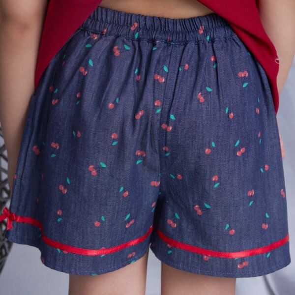 Back view of a girl wearing navy blue cherry printed shorts with satin ribbon bows