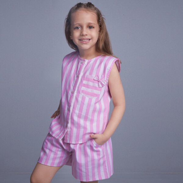 Hand inserted in the pocket, a little girl stands in a pink stripes co-ords set