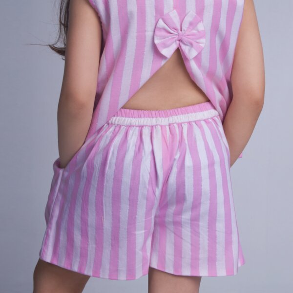 A girl is seen from the back, wearing a pink striped sleeveless blouse with a slit at the back, paired with shorts featuring a dual pockets