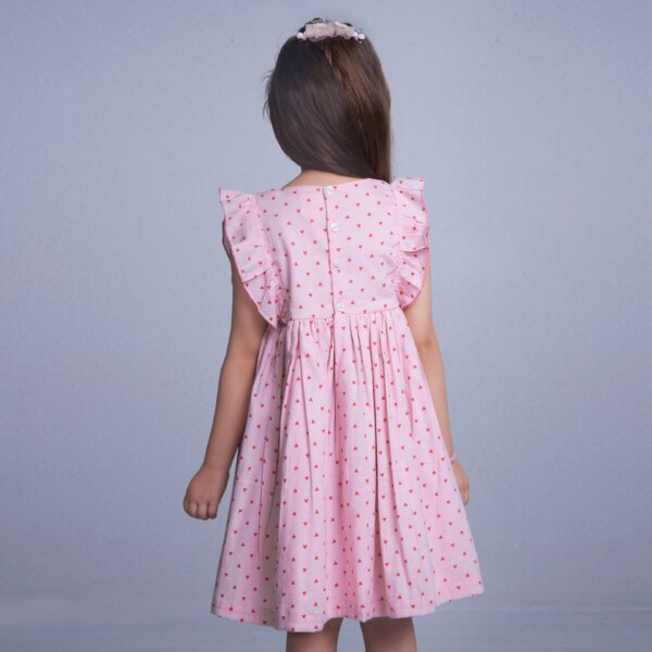 Back view of a girl dressed in pink heart printed embroidered smock dress