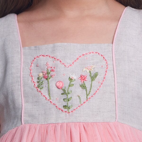 Detailed closeup of heart floral embroidery on a peach tulle dress