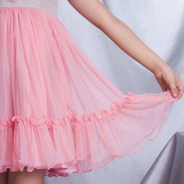 A detailed close-up of the peach tulle ruffle skirt on an embroidered dress