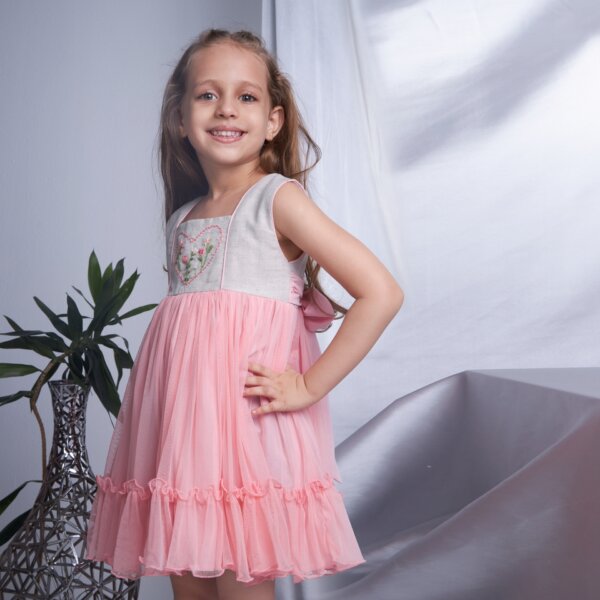 A young girl in sleeveless peach heart floral embroidered ruffle dress