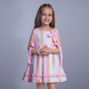 With hands tied, a pretty girl smiles brightly in a pink lurex dress with ruffle details